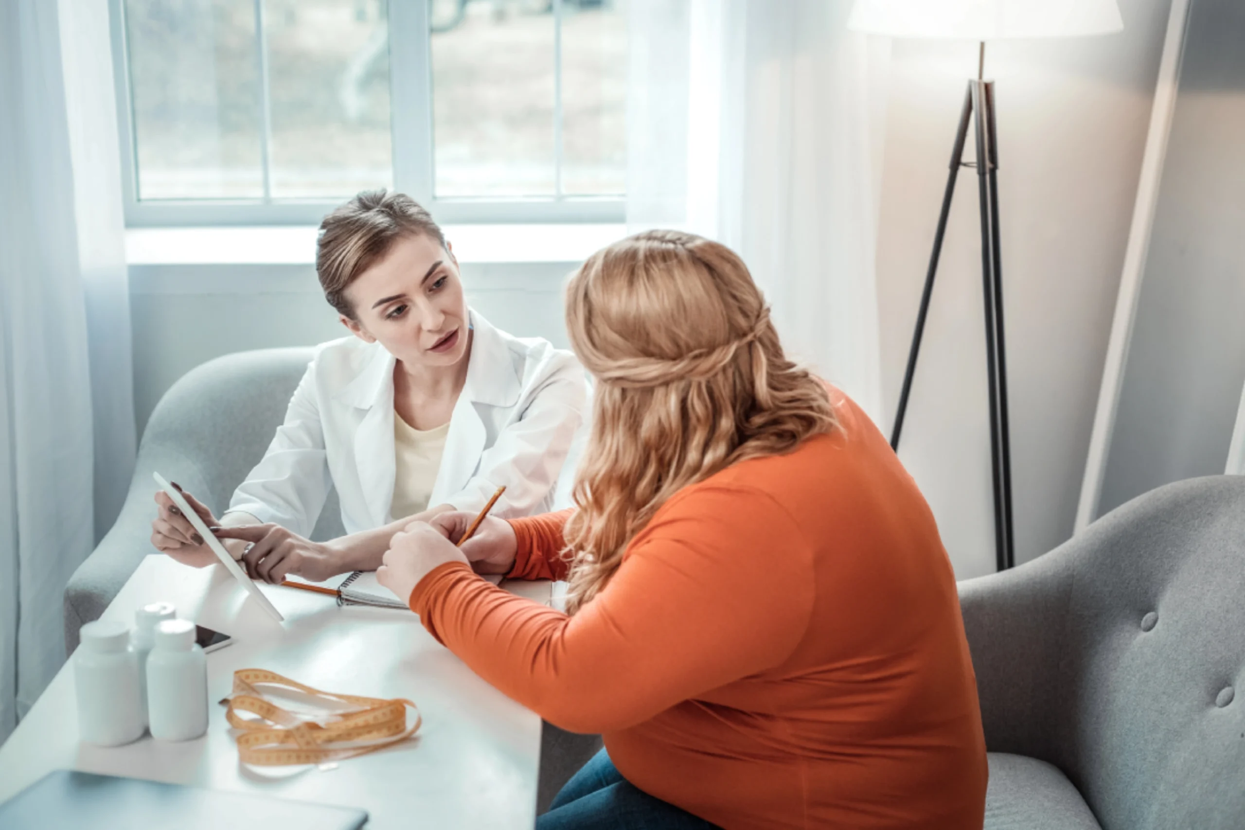 Medical weight loss Houston consultation with doctor discussing health plan, supplements, and body measurements.