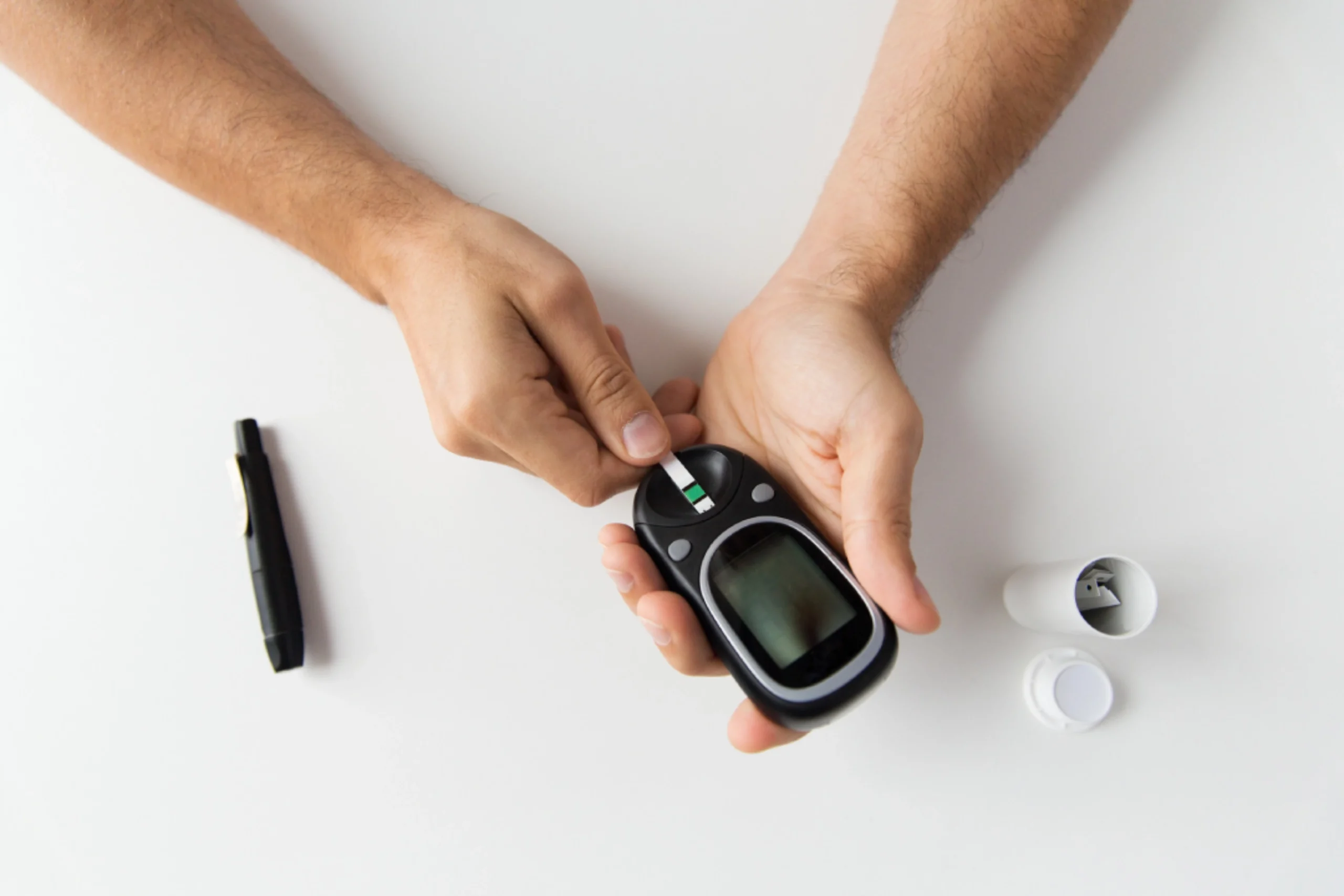 Patient checks blood sugar during prediabetes weight loss program using glucose meter and lancet for daily tracking.