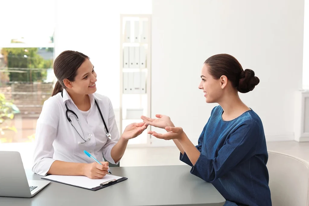 Doctor with stethoscope consults smiling patient across desk at weight loss clinic Houston in bright room.
