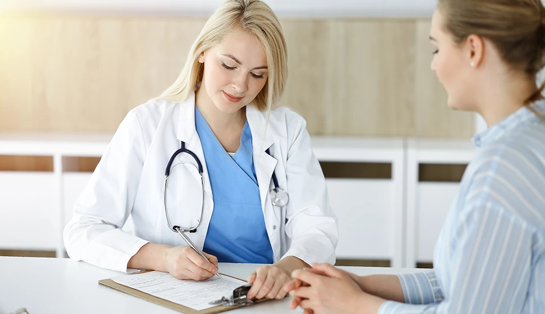 Pregnant patient consults with healthcare provider writing notes at weight loss clinic Houston in a cozy office.