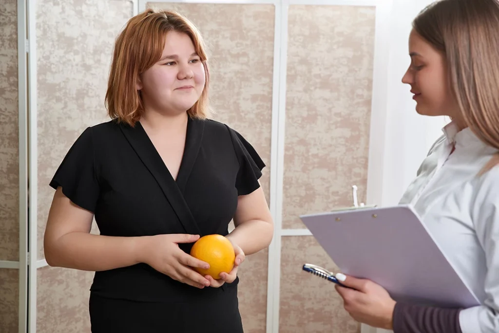 Patient holds an orange while consulting with a professional at a weight loss clinic Houston.