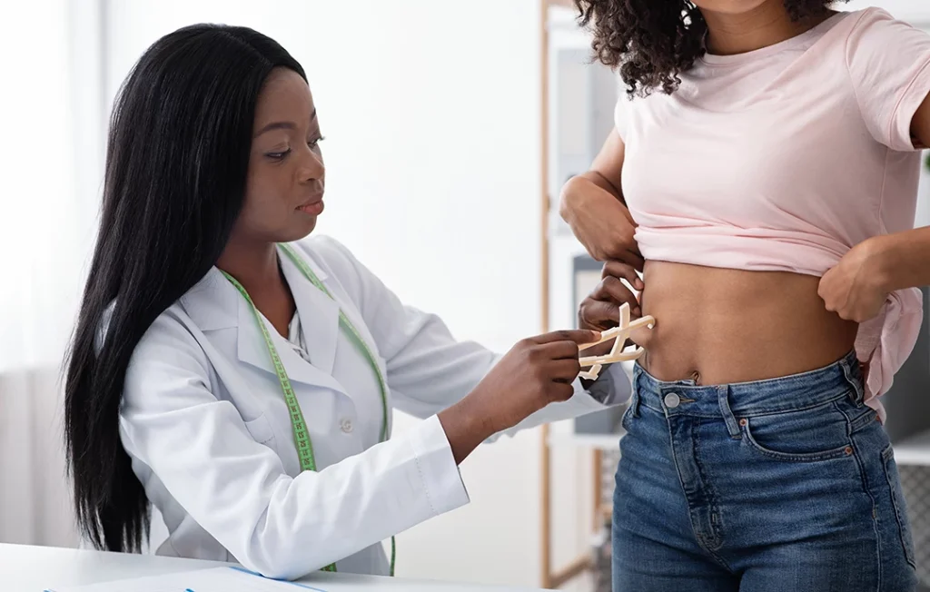 A healthcare provider uses calipers to measure a patient at a weight loss clinic Houston in a bright office.