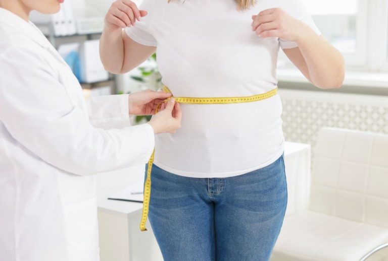 Doctor measuring patient’s waist in clinic during Weight Loss Injections Houston consultation for fat reduction.