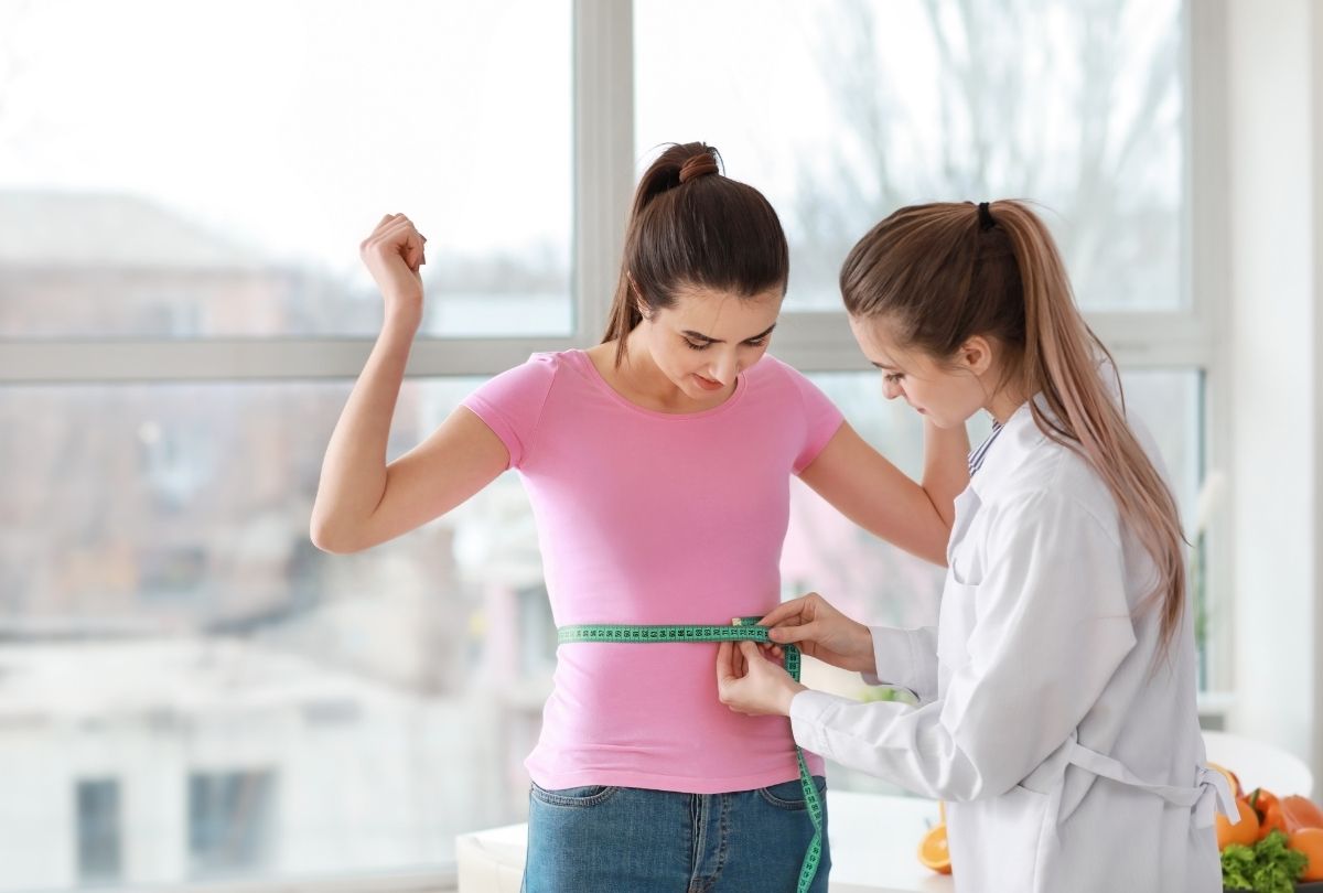 Weight loss shots Houston—healthcare provider evaluates waist size during consultation for weight loss and wellness goals.