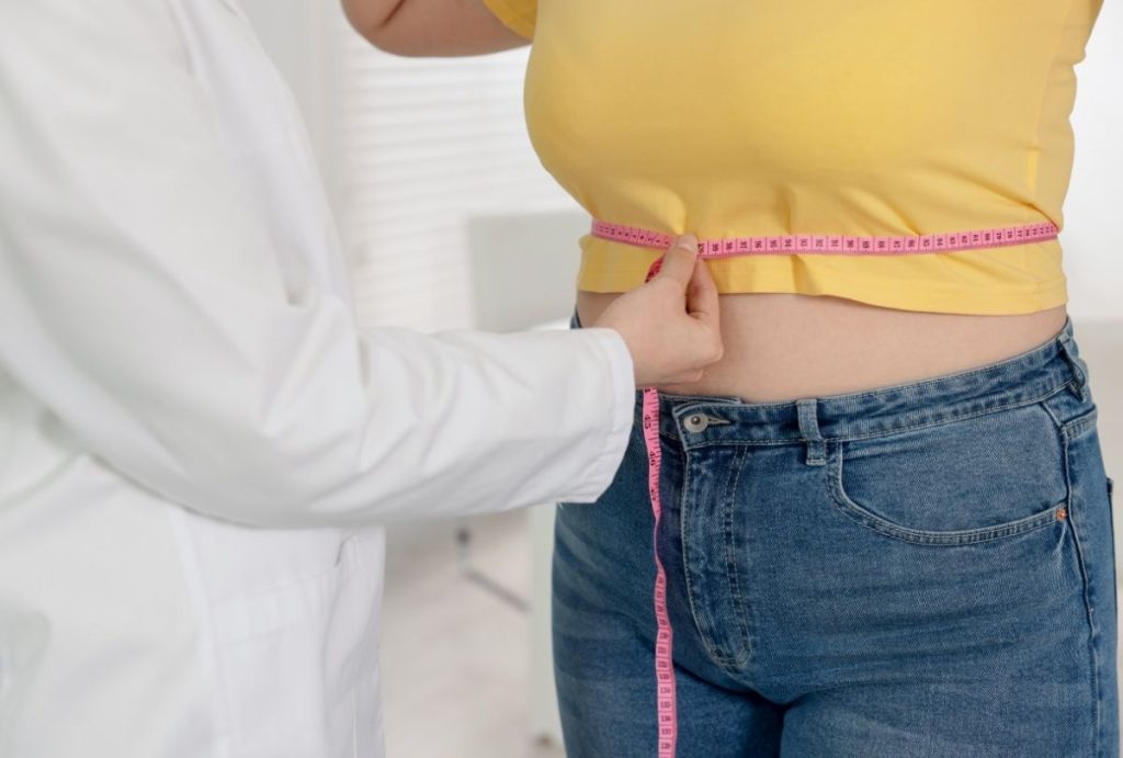 Weight loss shots Houston—healthcare provider measures waistline to track progress during weight management consultation.