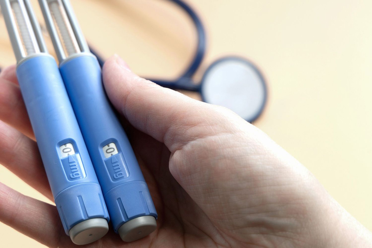 Holding two pens to illustrate correct Semaglutide dosage levels for Semaglutide Cost Houston treatment plans.