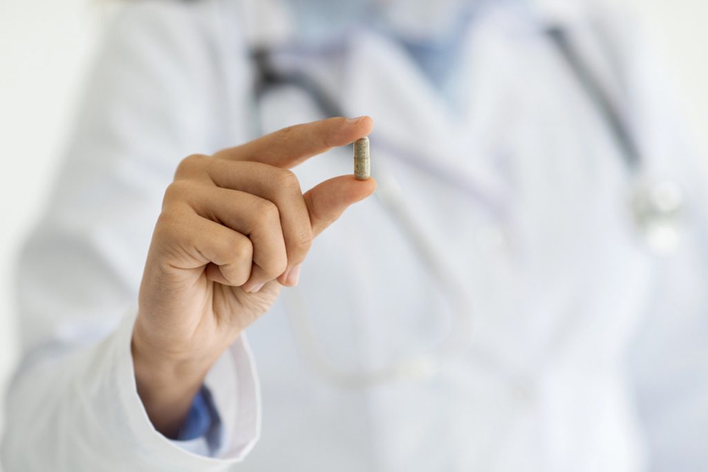 Doctor holding capsule in gloved hand, symbolizing prescription-based Medical Weight Loss Houston plans monitored by healthcare professionals.