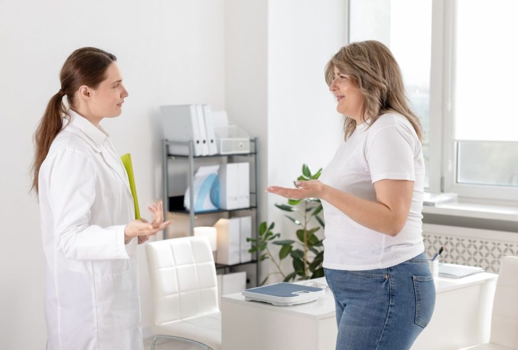 Healthcare provider in white coat holding a yellow folder during a weight loss consultation with a patient in a medical office.