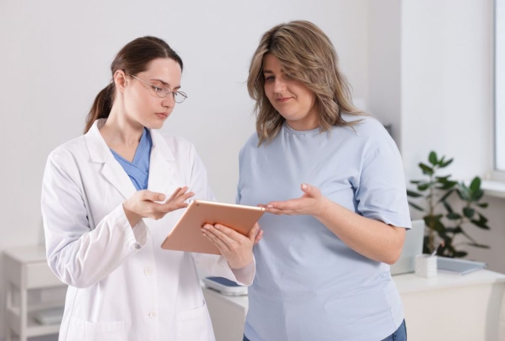 Medical professional discussing treatment options with patient using a tablet in a clinical setting.