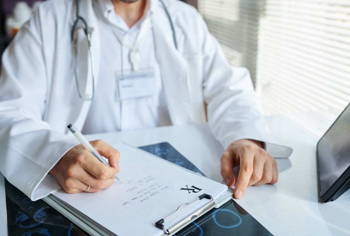 Doctor writing Rx at weight loss clinic Houston, prescribing medication with stethoscope and tablet in bright office.
