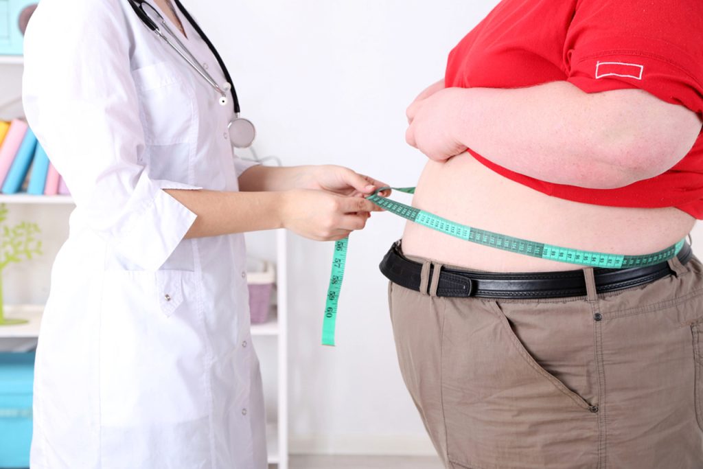 Doctor measures patient waist circumference in clinic to evaluate obesity risks and discuss Semaglutide Houston medical weight loss options
