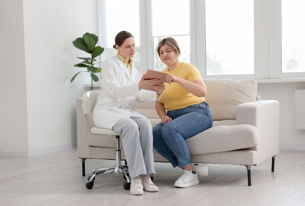 Doctor and patient reviewing tablet together in a bright medical office, highlighting collaborative weight loss planning.