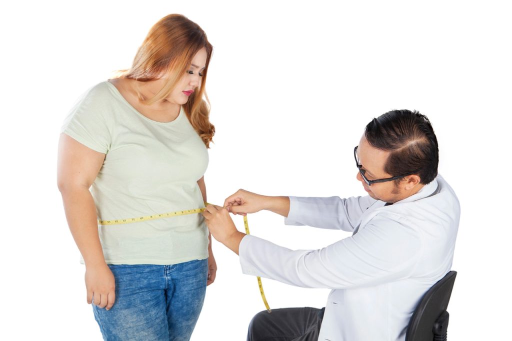 Weight loss doctor in Houston measuring patient's waist circumference during consultation to track progress and tailor effective obesity management strategies.