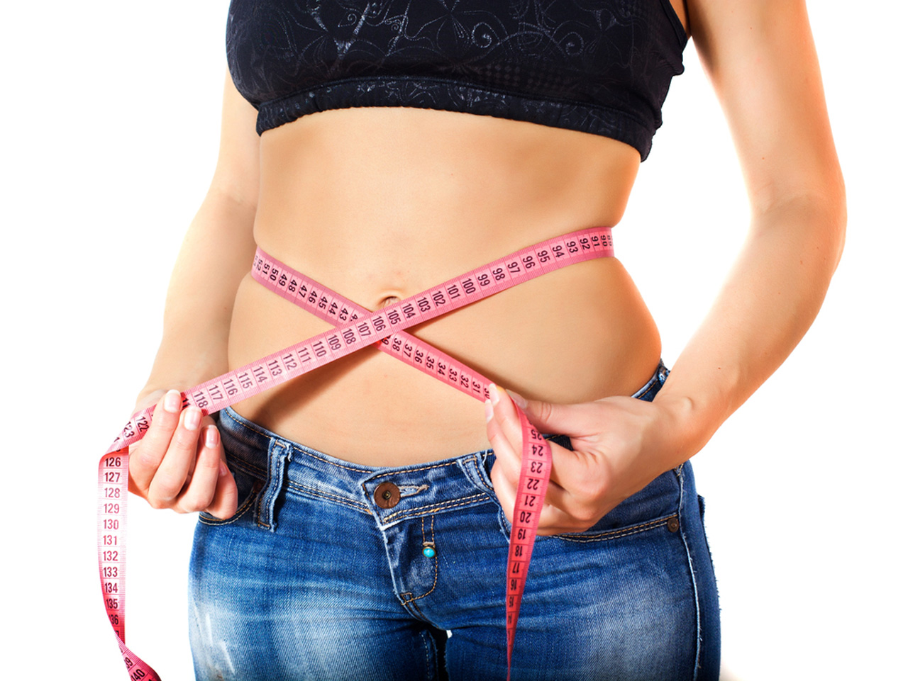 Woman in jeans self-measuring waist with pink tape, achieving sustainable results through personalized plan from top weight loss doctor in Houston.