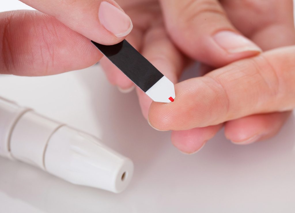 Patient performing a finger prick glucose test during a health screening at a Semaglutide Houston diabetes care center.