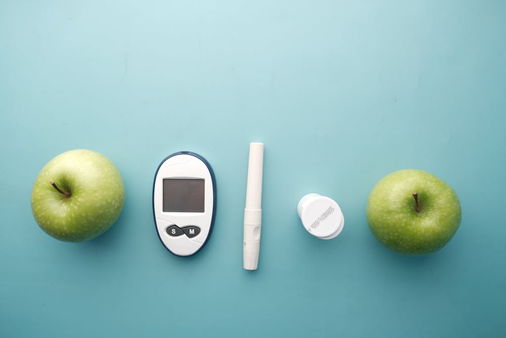 A diabetes testing kit alongside green apples on a blue background, symbolizing health and diet management.