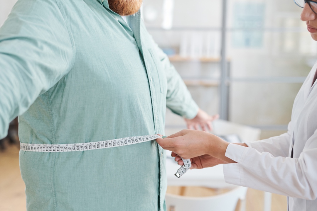 A doctor takes a waist measurement of a patient using a tape measure as part of an assessment at a glp-1 clinic houston.