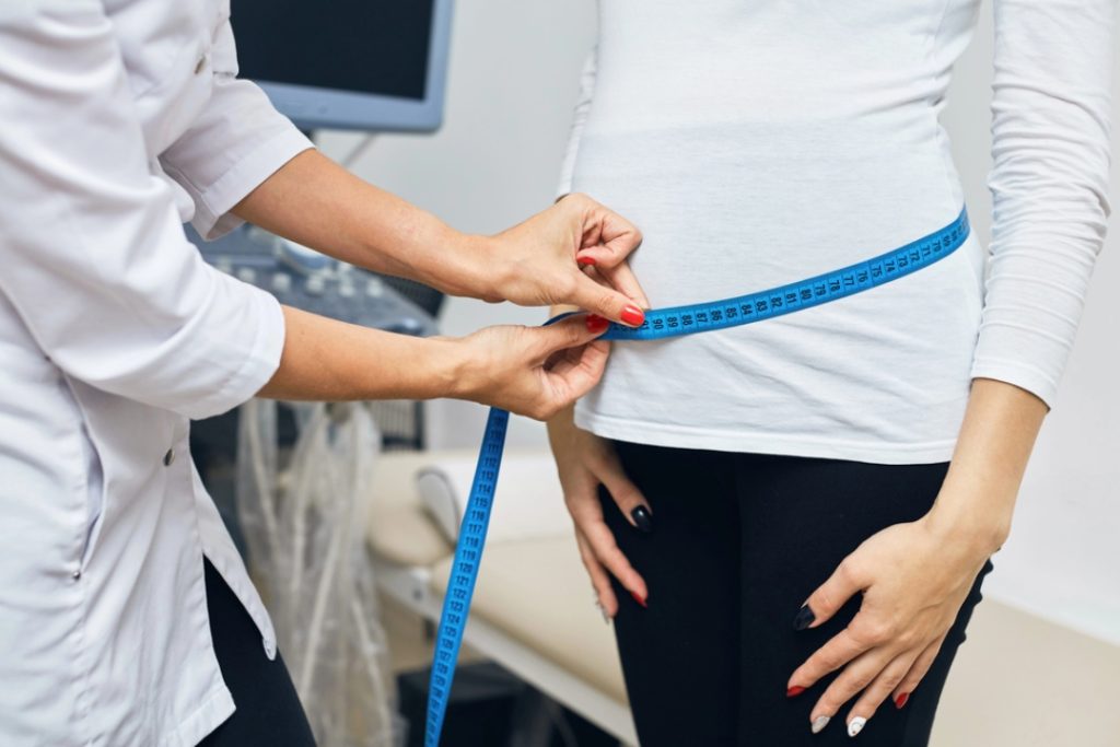 A female doctor measuring a patient's waist during a consultation for weight loss injections Houston residents trust.