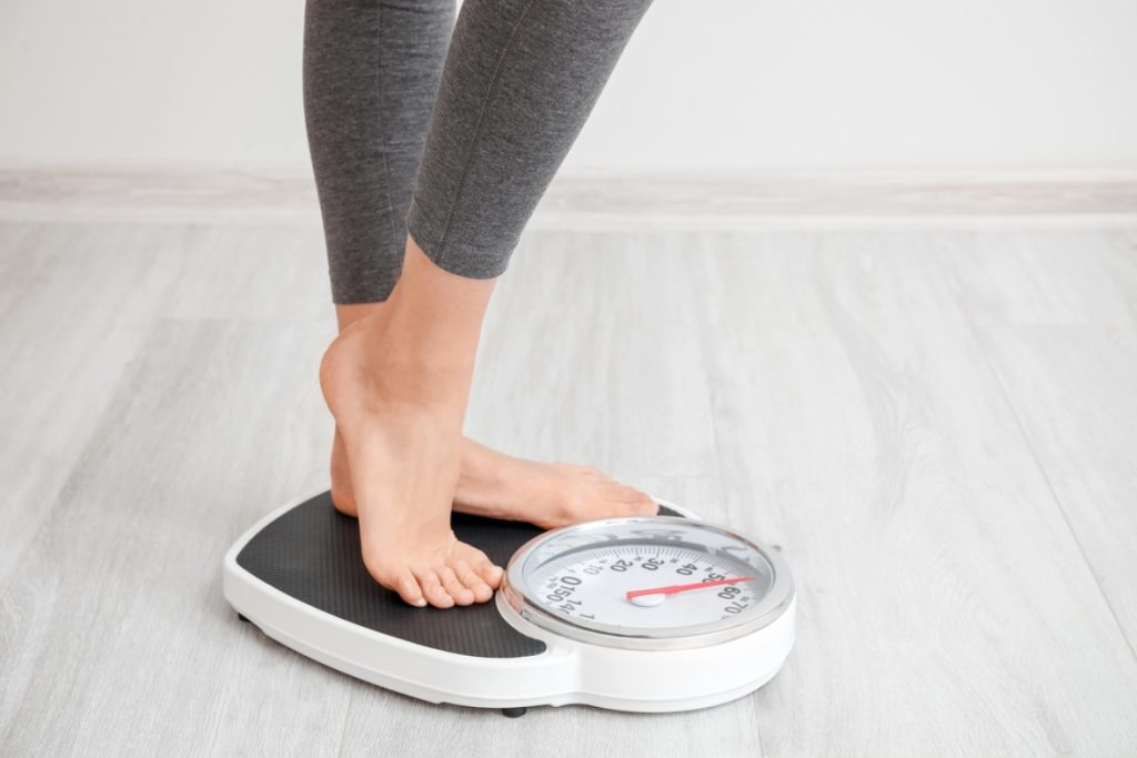 Person standing on an analog scale to monitor progress during their GLP-1 weight loss Houston journey