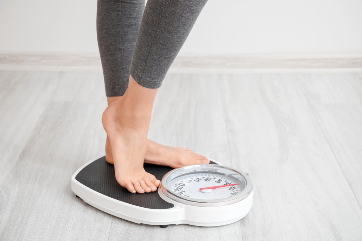 Person standing on an analog scale to monitor progress during their GLP-1 weight loss Houston journey