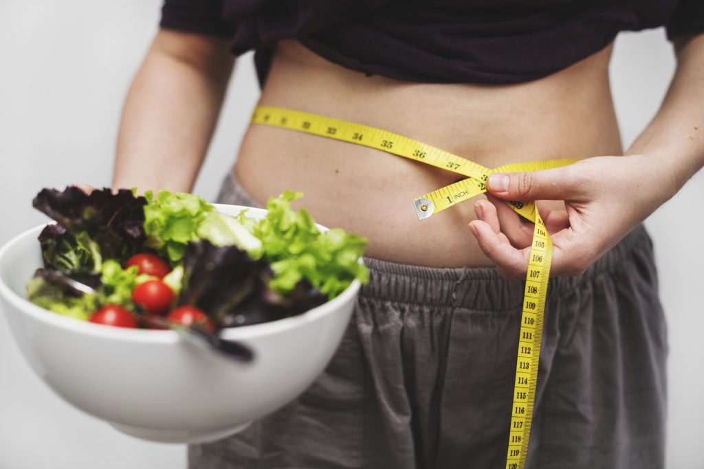 Woman measuring her tummy and weight for weight loss in Houston