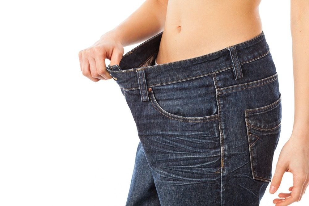 Close-up of woman in dark jeans showing how large they are on her waist after weight loss clinic Houston care.