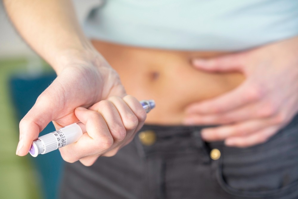A close-up view of a person self-administering an injector pen into their abdomen for weight loss shots Houston.