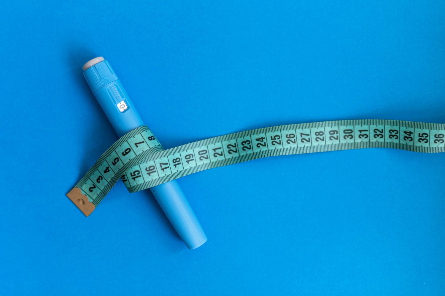 Medical pen for weight loss injections Houston patients use, wrapped in a measuring tape to show fitness progress.