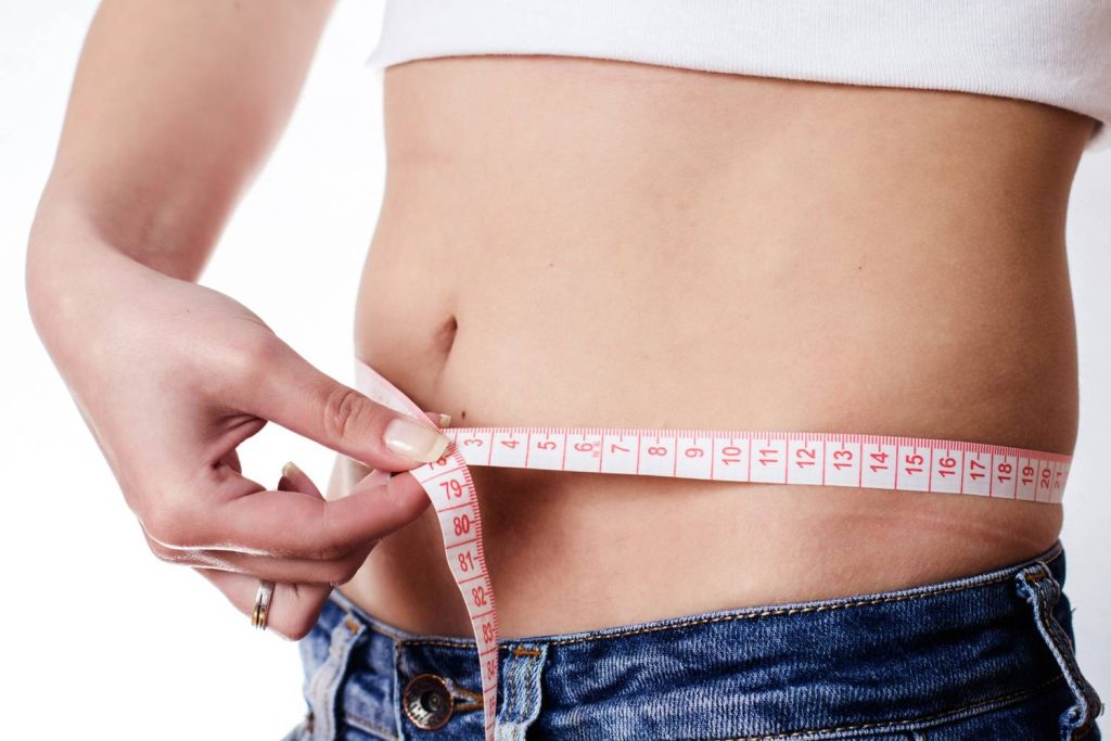 Close up of a woman tracking her waist measurement progress while using Mounjaro for weight loss Houston clinic.