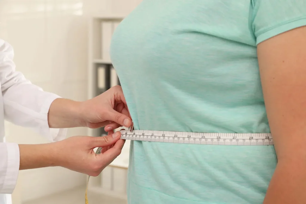 A patient at a medical clinic in Houston gets waist measured, considering weight loss injections for effective treatment.